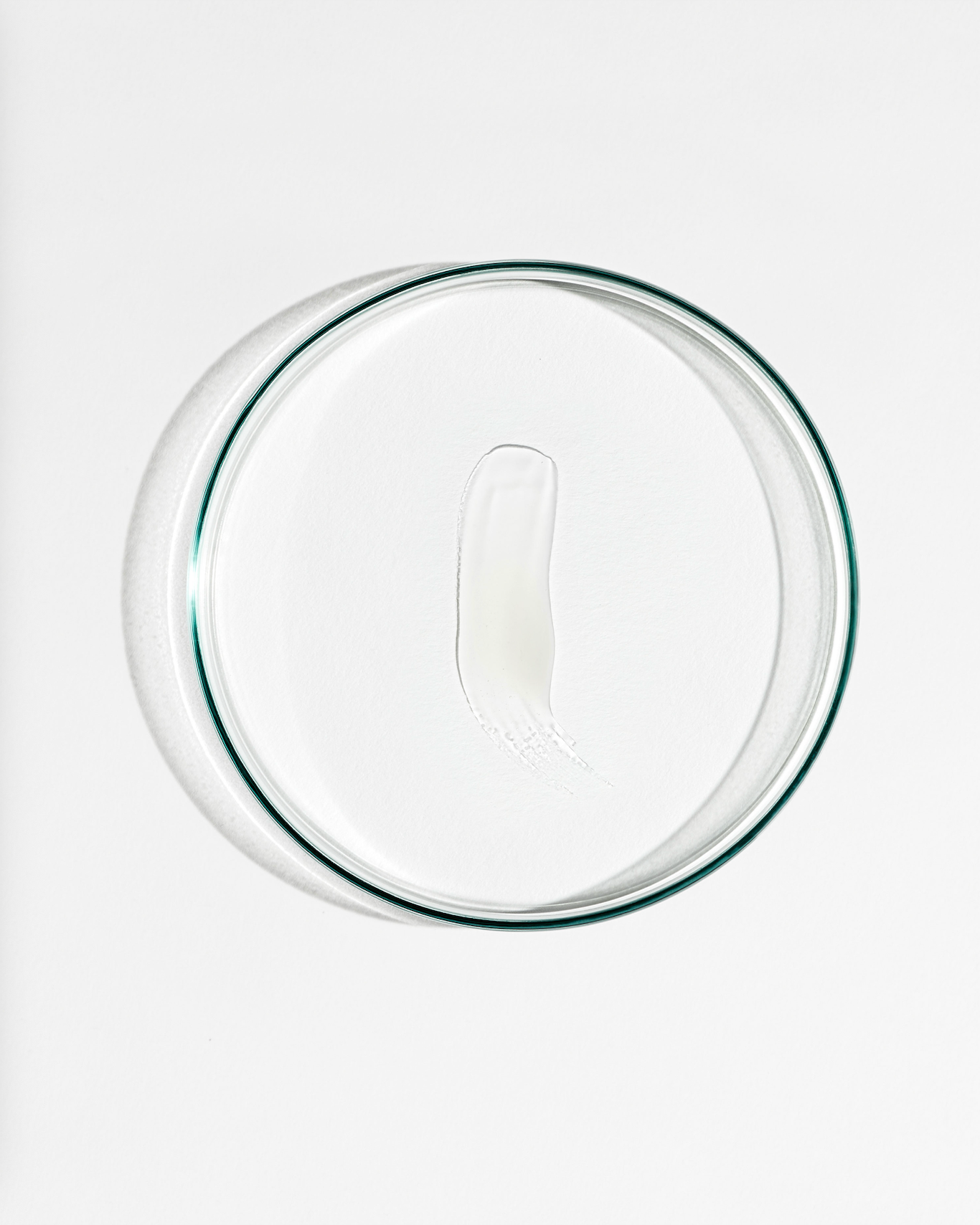 Clear dish with a smudge of cream agaisnt a white background