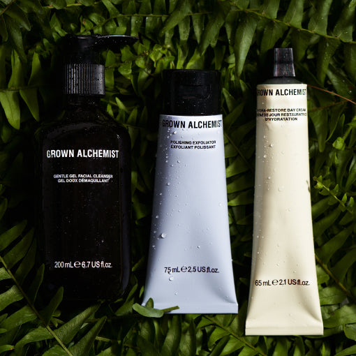 Three Grown Alchemist skincare products on a green leaf background