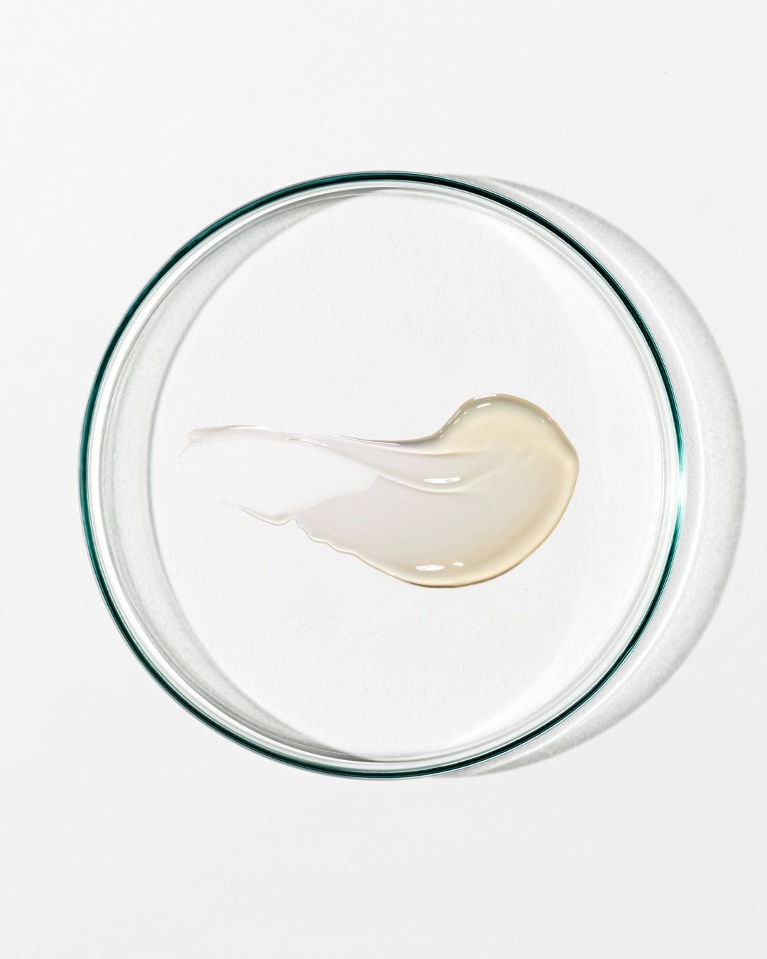 Glass bowl with a small amount of white cream on a white background