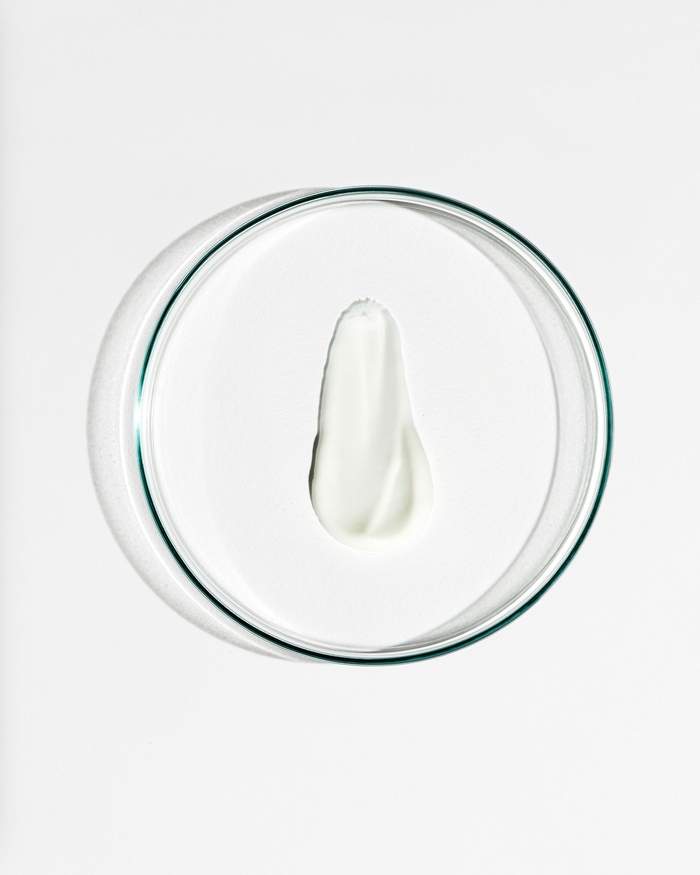 Clear dish with a dollop of white cream on a white background