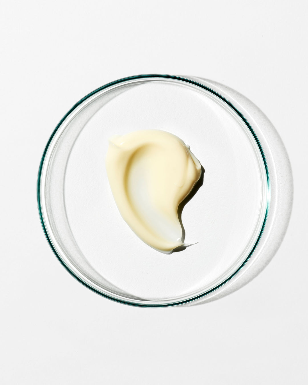 Glass bowl with a swirl of cream on a white background