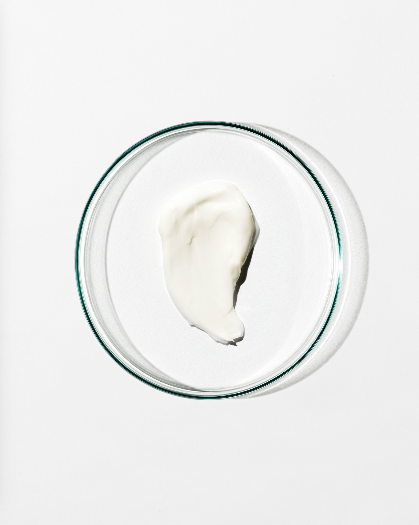 Glass bowl with a dollop of white cream on a white background