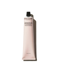 Pink tube of Brown Alchemist hand cream on a white background