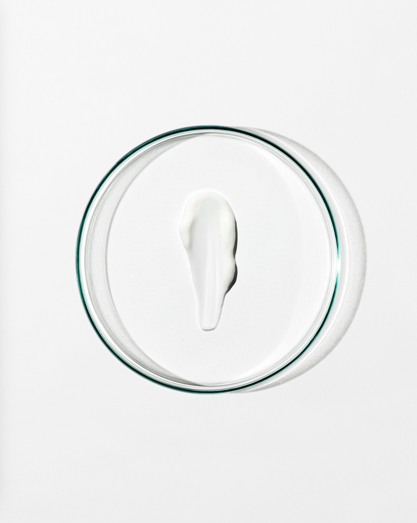 Clear dish with a dollop of white cream against a white background