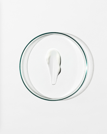 Clear dish with a dollop of white cream against a white background