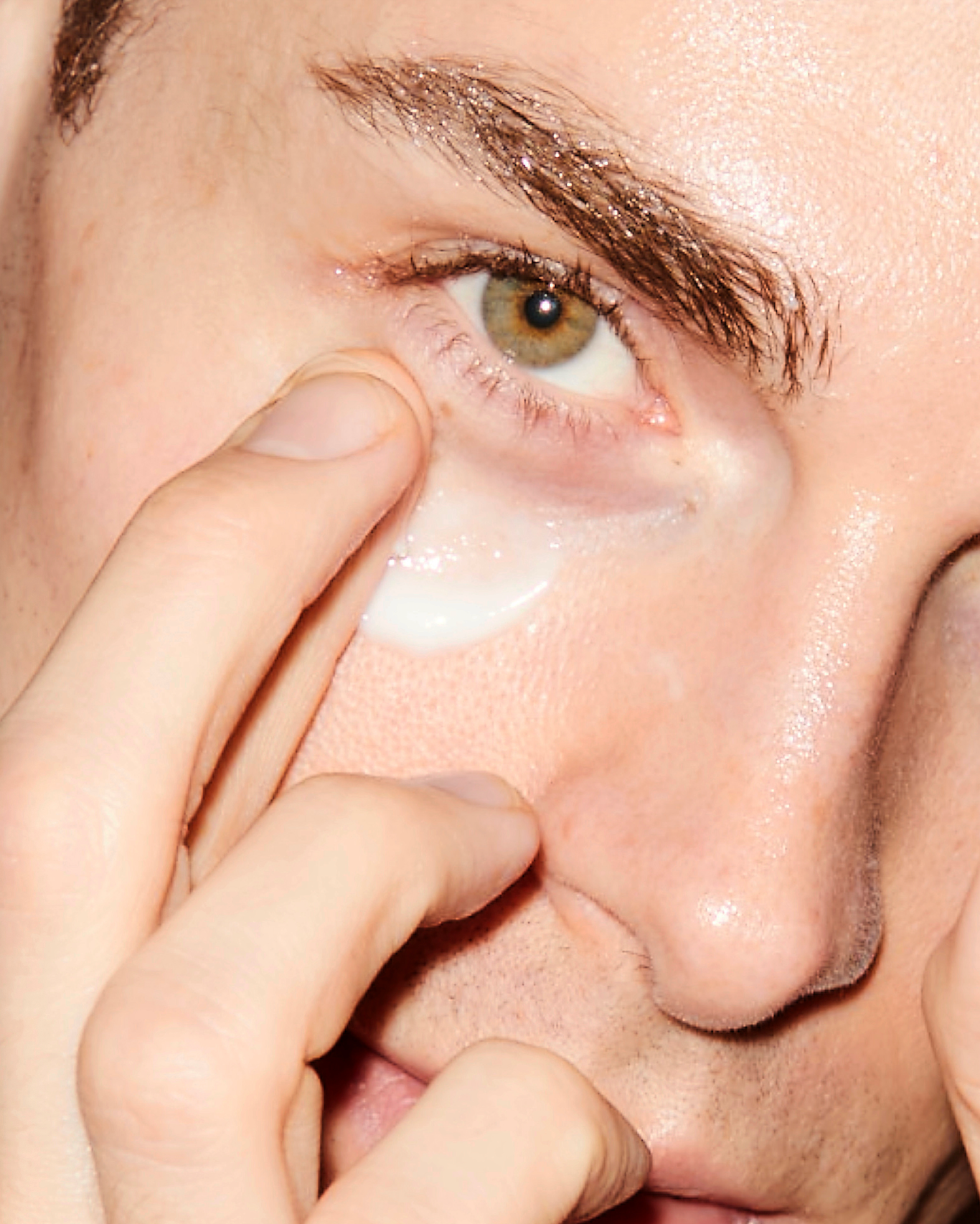Close up of a person applying white cream under their eye