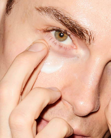 Close up of a person applying white cream under their eye