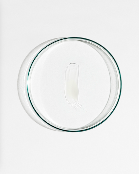Clear dish with a smudge of cream agaisnt a white background