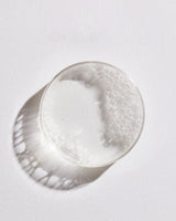 Petri dish with toner liquid and foam against white background.
