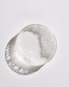 Petri dish with toner liquid and foam against white background.