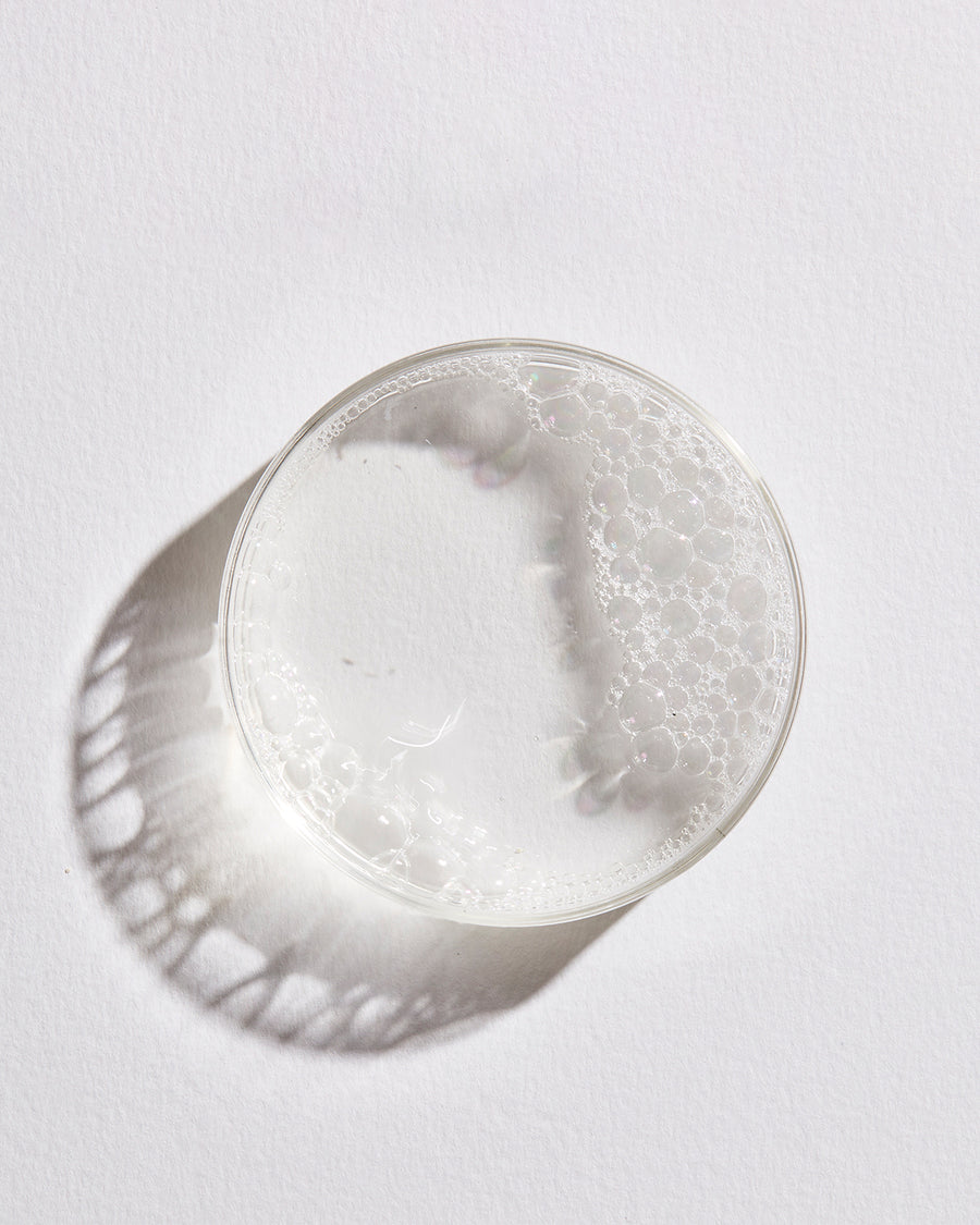Petri dish with toner liquid and foam against white background.