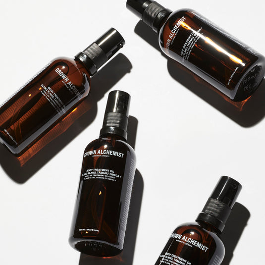 Four bottles of Grown Alchemist oil scattered against a white background