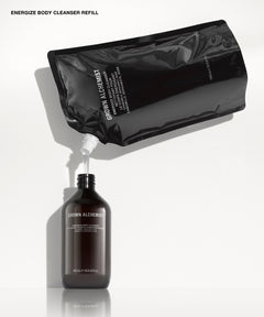 A black refill pouch labeled 'GROWN ALCHEMIST' pouring a liquid into a dark amber bottle also labeled 'GROWN ALCHEMIST' on a clean white background.