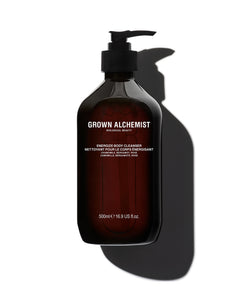 A 500ml pump bottle of Grown Alchemist Enriched Body Cleanser, made of dark amber-brown translucent plastic with a black pump dispenser. The bottle is centered against a clean white background, casting a prominent dark shadow to the right.