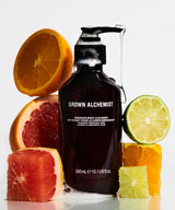 A 300 mL pump bottle of Grown Alchemist body cleanser, styled with fresh citrus fruits including orange, grapefruit, and lime slices on a clean white background.