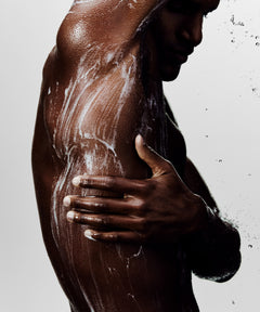 Shot of man in shower rinsing his body with cleanser.