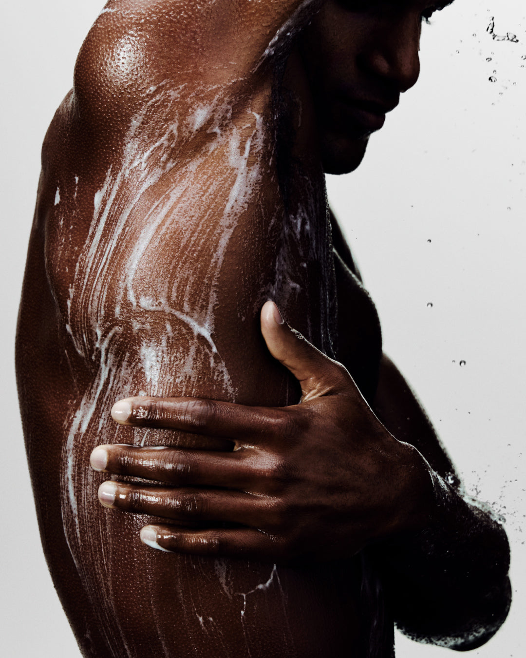 Person with soap suds on their body against a white background