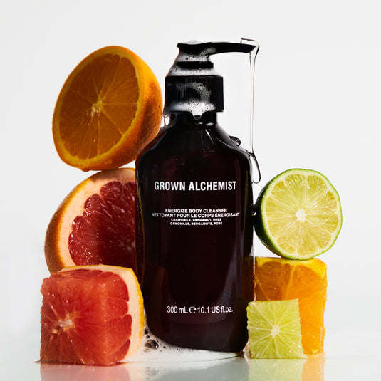 Grown Alchemist bottle with citrus fruits on a white background
