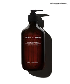 A 500ml pump bottle of Grown Alchemist Exfoliating Hand Wash in an amber brown glass bottle with a black pump dispenser, casting a sharp shadow on a white background.