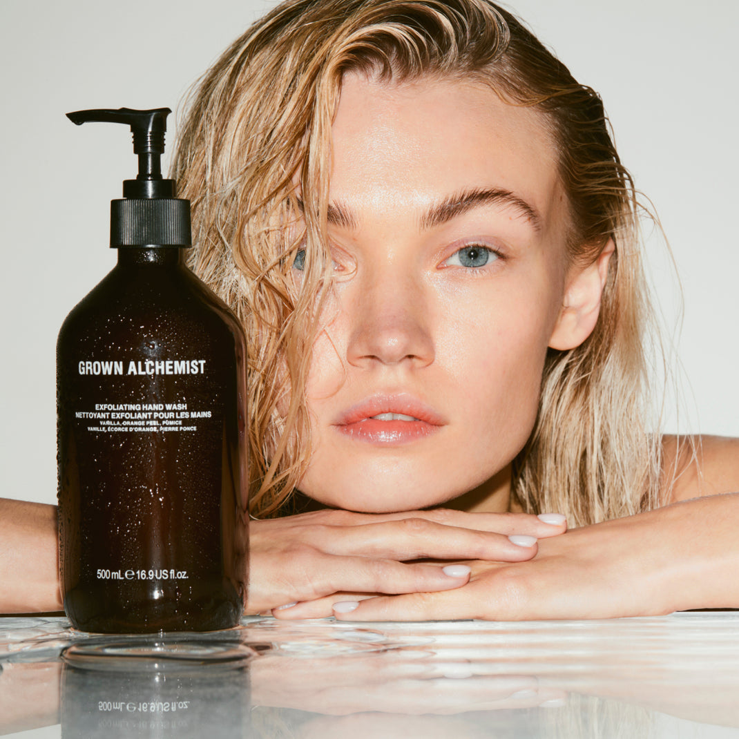 Woman with a bottle of Exfoliating Hand Wash on a reflective surface