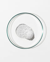 Clear petri dish with a small amount of white foam on a white background