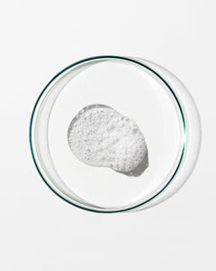 Clear petri dish with a small amount of white foam on a white background