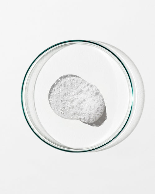 Clear glass bowl with a small amount of white foam on a white background