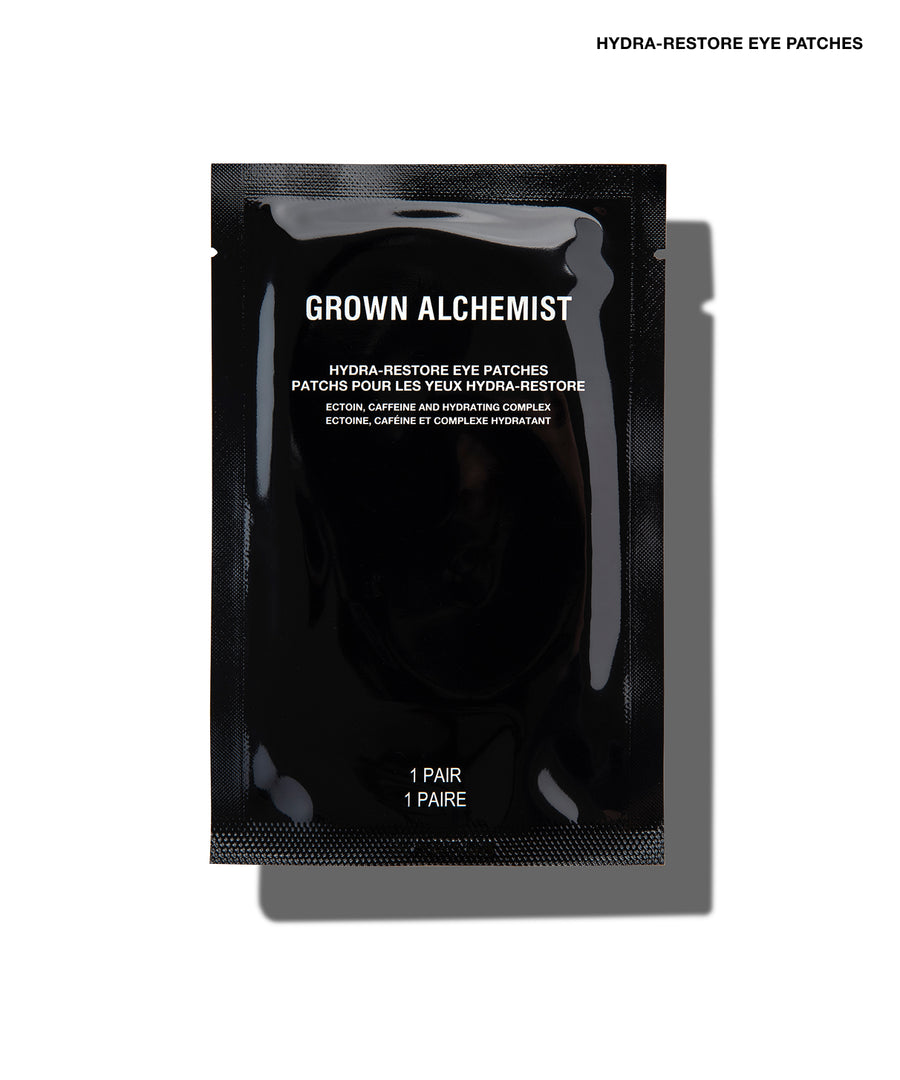 A single black Grown Alchemist Hydra-Restore Eye Patch sachet on a white background with a soft shadow.