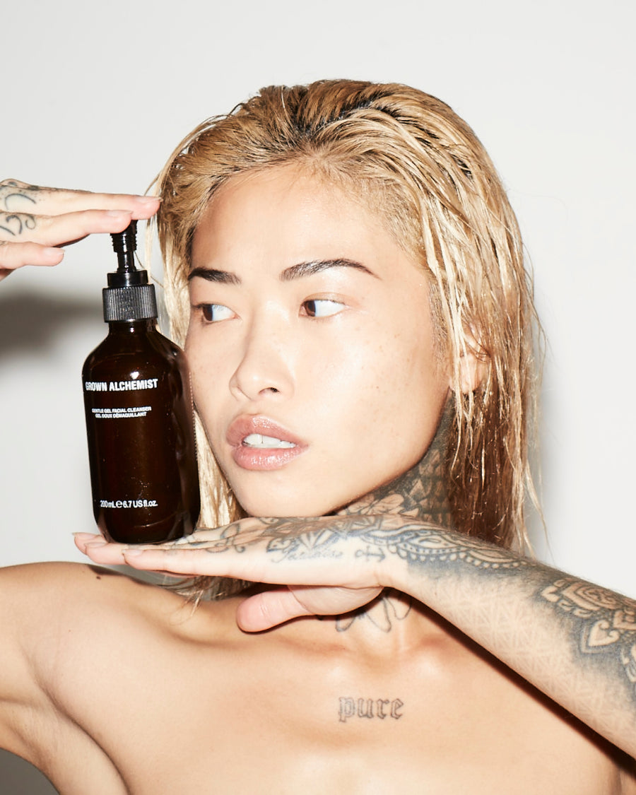 Person holding a bottle of 'Grown Alchemist Gentle Gel Facial Cleanser' product with a neutral background