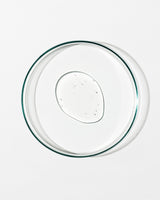 Clear glass pie dish with a dollop of gentle gel facial cleanser on a white background