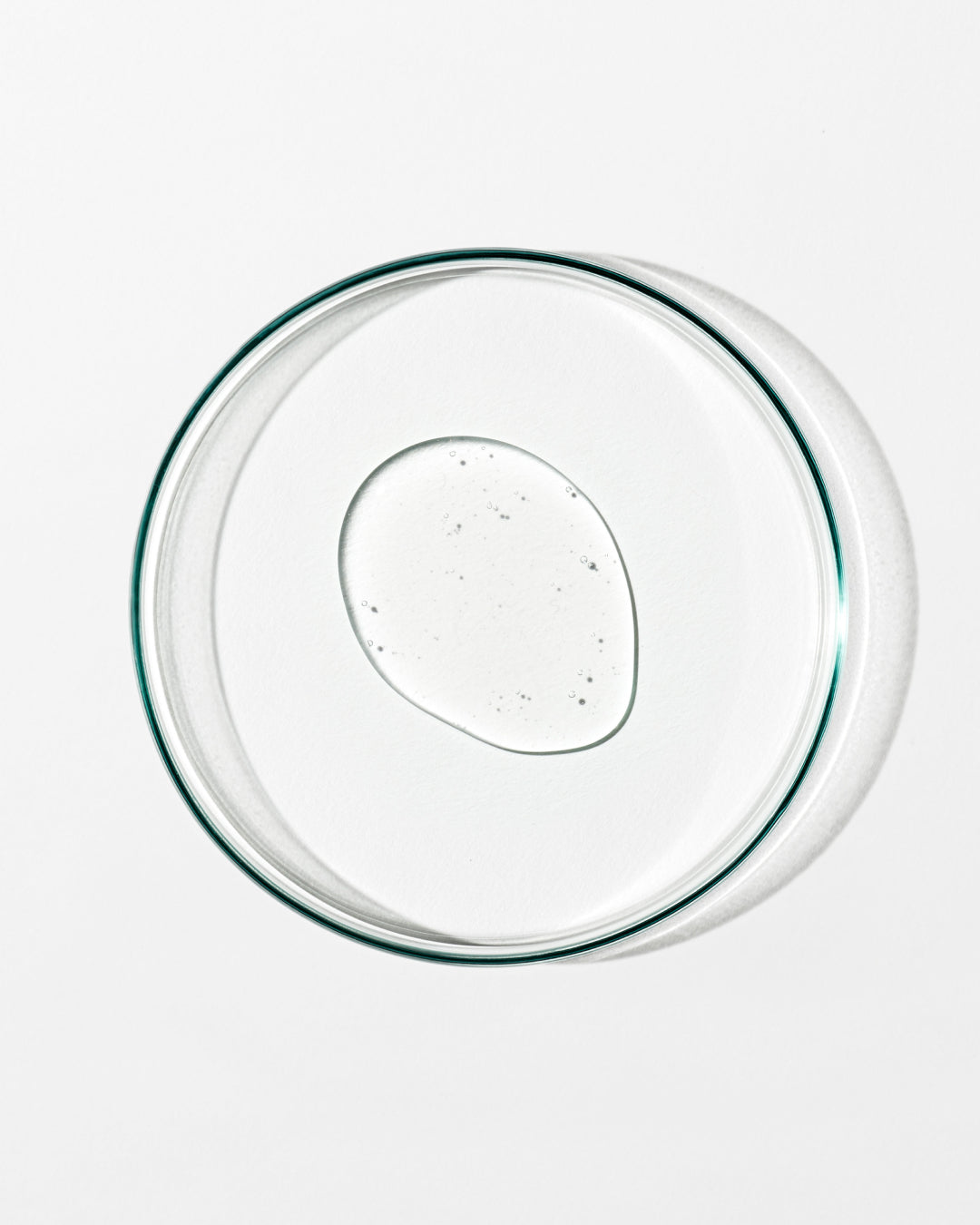 Clear glass pie dish with a dollop of clear liquid on a white background
