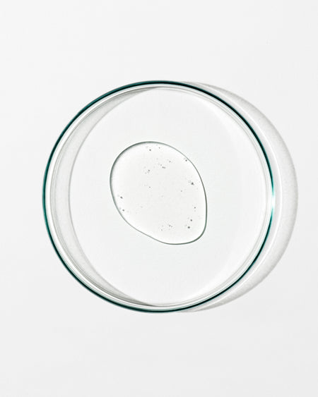 Clear glass pie dish with a dollop of clear liquid on a white background