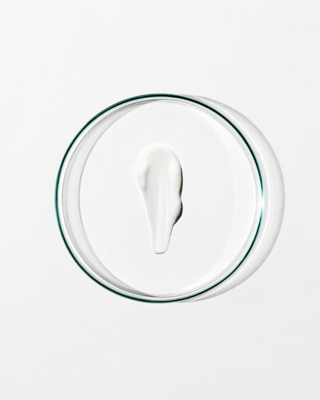 Glass lid with a circular dollop of cream on a white background