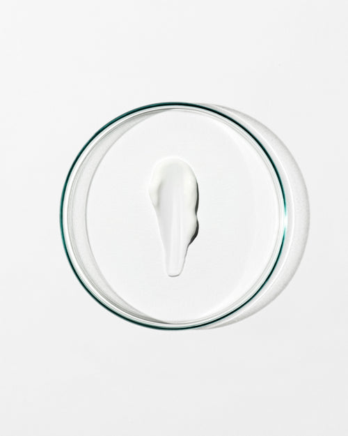 Glass lid with a circular dollop of cream on a white background
