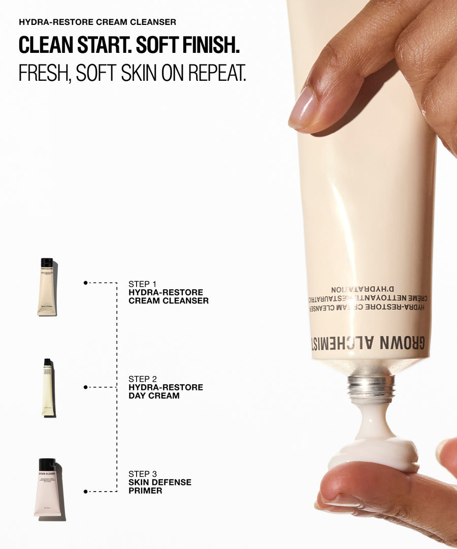 A hand squeezes a cream tube of Brown Allchemists Hydra-Restore Cream Cleanser against a white background with product text and small step-by-step skincare bottle illustrations on the left.