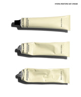 Three squeeze tubes of Brown Alchemy Hydra-Restore Day Cream arranged vertically on a white background, with the brand name and product name printed at the top right.
