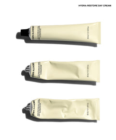 Three squeeze tubes of Brown Alchemy Hydra-Restore Day Cream arranged vertically on a white background, with the brand name and product name printed at the top right.