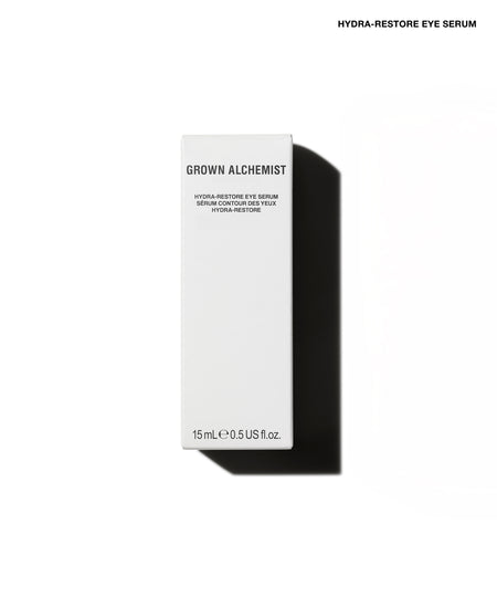 A tall, slim white rectangular box for Grown Alchemist Hydra-Restore Eye Serum, shown on a clean white background with a strong black shadow to the right. Small black text at the top right reads 'HYDRA-RESTORE EYE SERUM'.