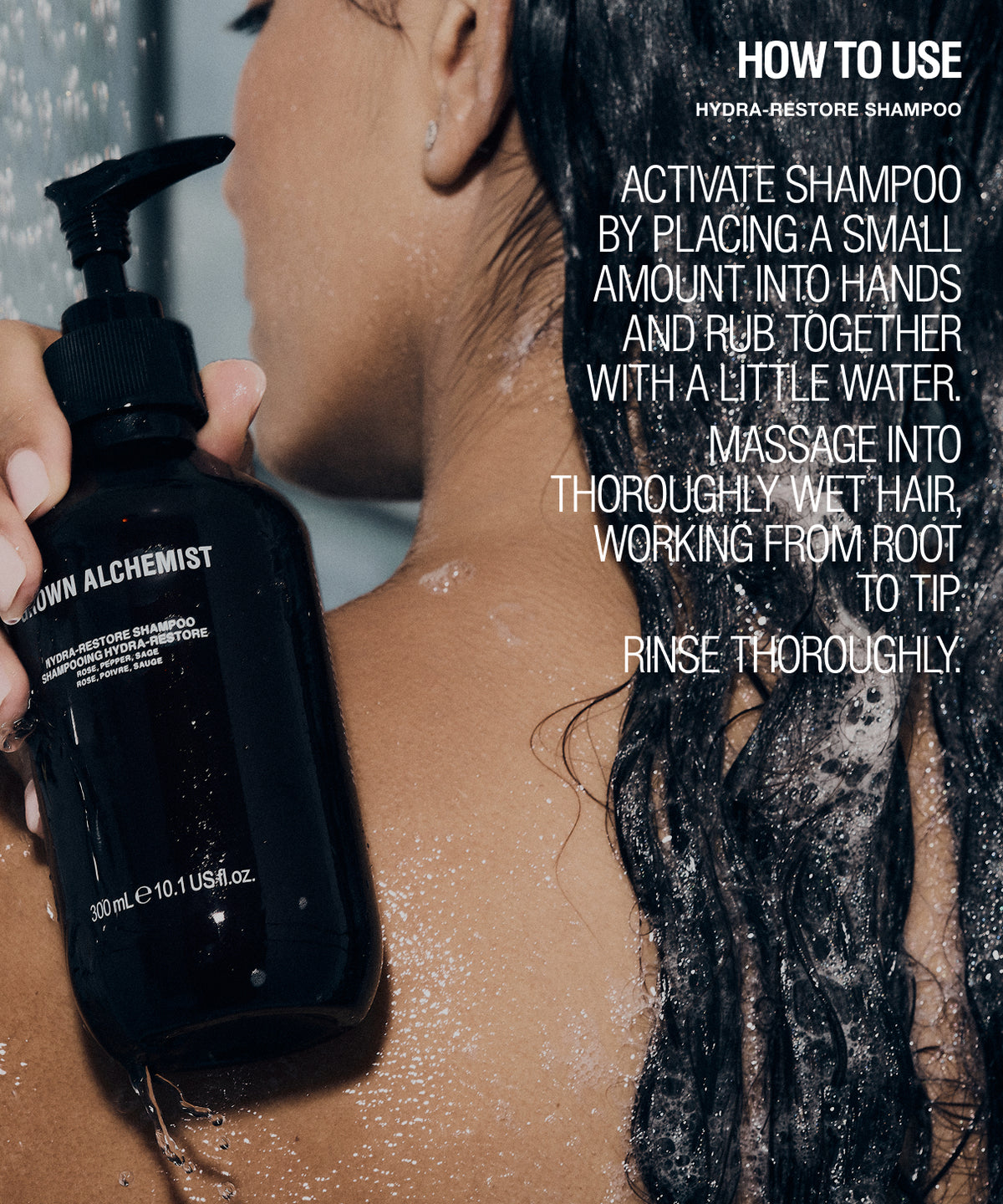 A person with wet dark hair holds a black pump bottle labeled 'Brown Alchemist' while reading a how-to-use overlay for Hydra-Restore shampoo.