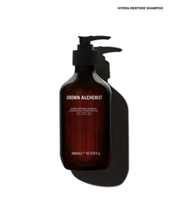 A 300mL dark amber glass pump bottle of Grown Alchemist Hydra-Restore Shampoo, shown on a white background with a dramatic shadow.