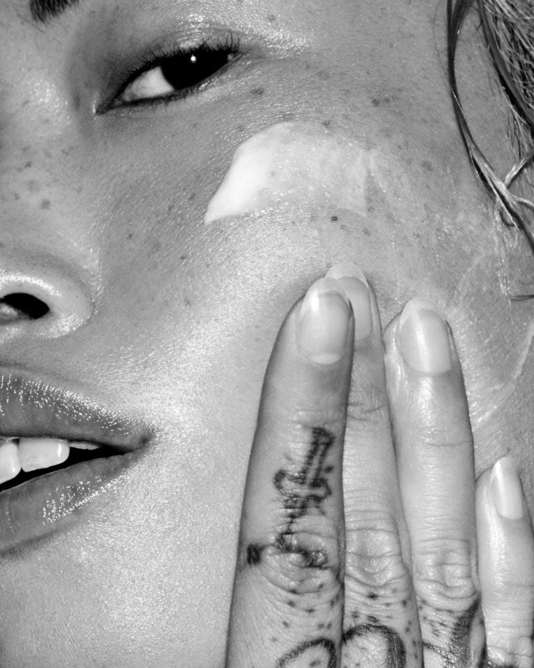 Close-up of a person with a tattoo on their finger near their face.