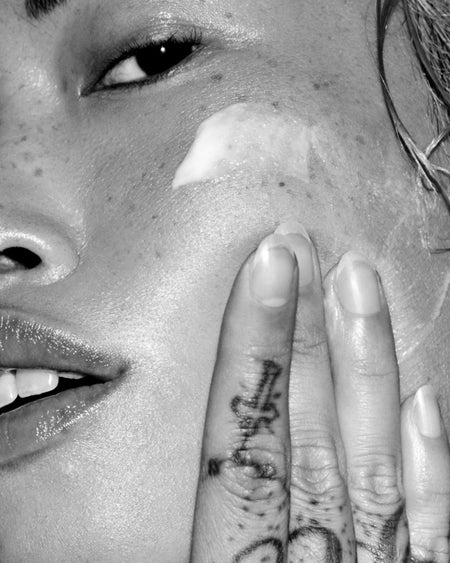 Close-up of a person with a tattoo on their finger near their face.