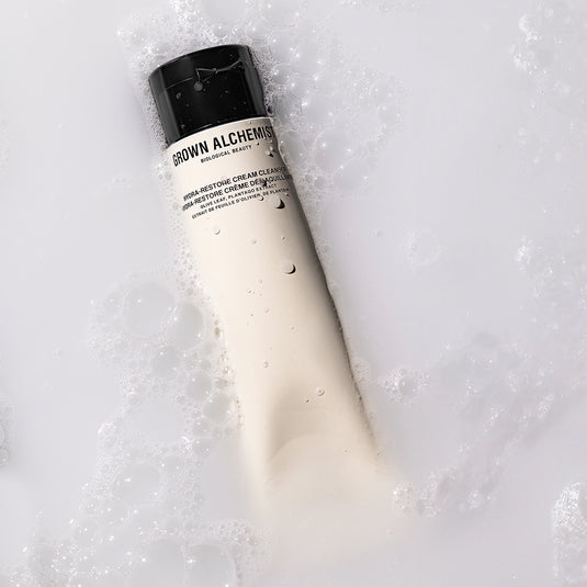 Bottle of Grown Alchemist cream cleanser on a textured white background