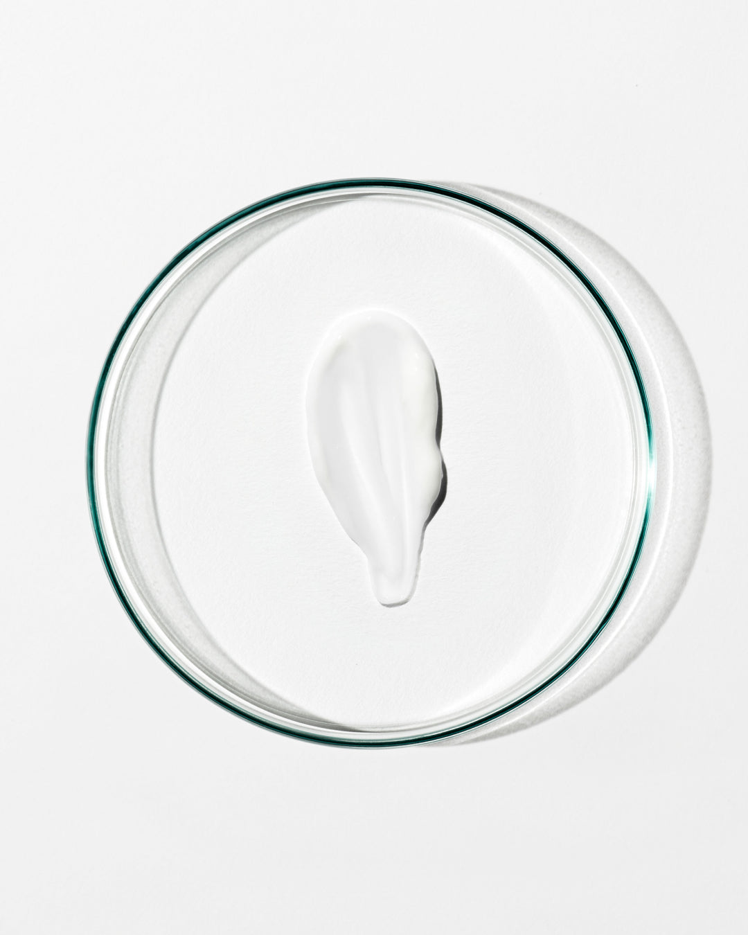 White cream in a clear glass bowl on a white background