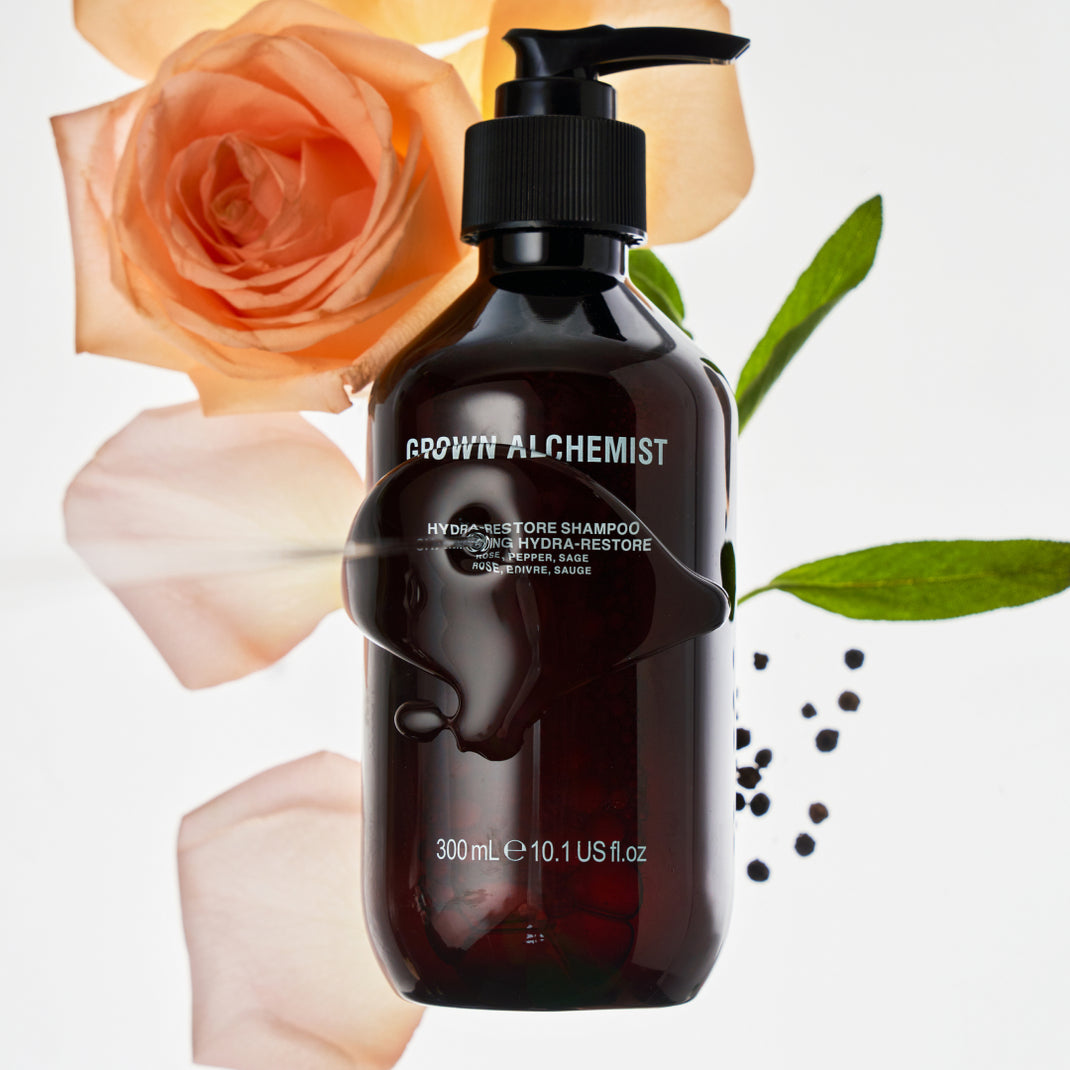 Grown Alchemist shampoo bottle with flowers and leaves on a light background
