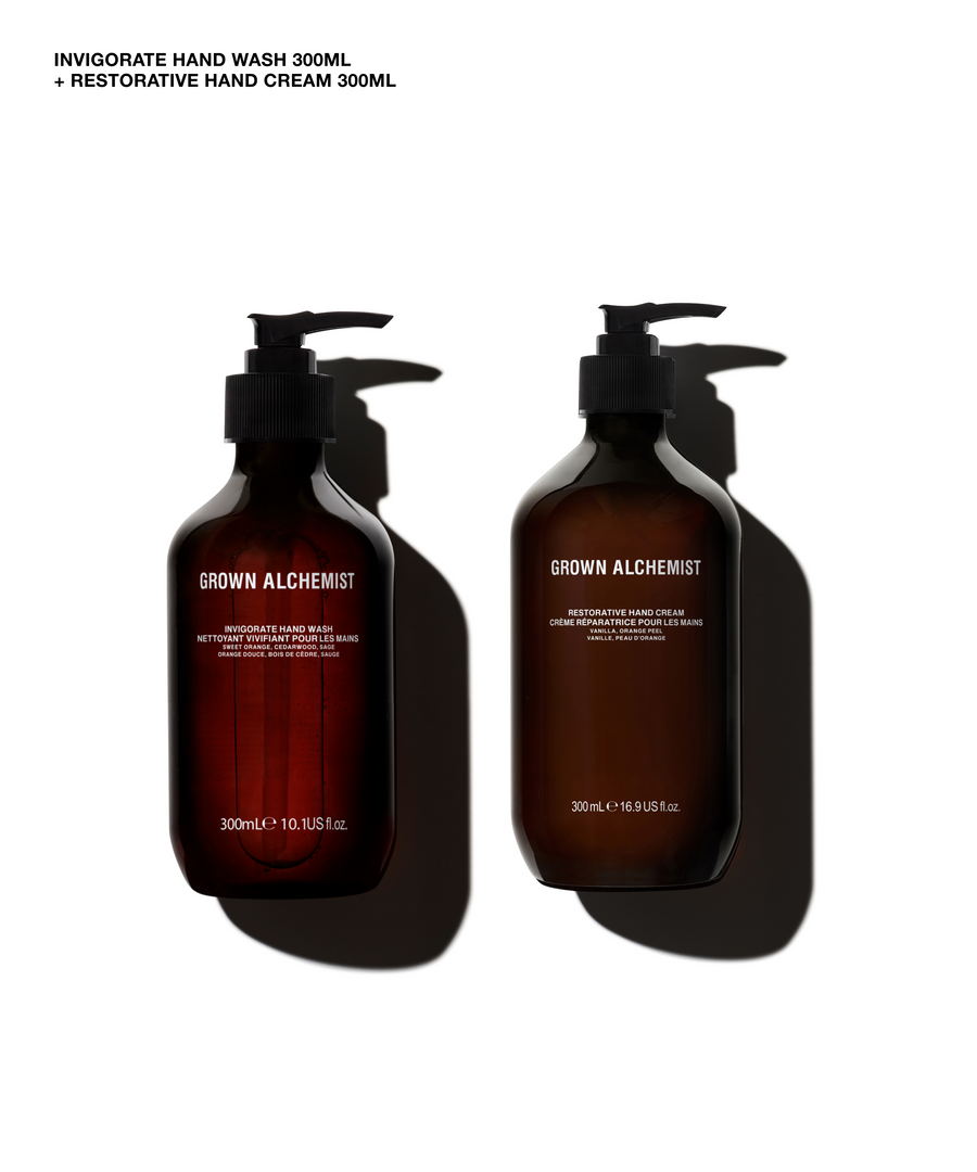 Two amber pump bottles of GROWN ALCHEMIST hand wash and hand cream on a white background with black shadows. Text at the top reads 'INVIGORATE HAND WASH 300ML + RESTORATIVE HAND CREAM 300ML'.