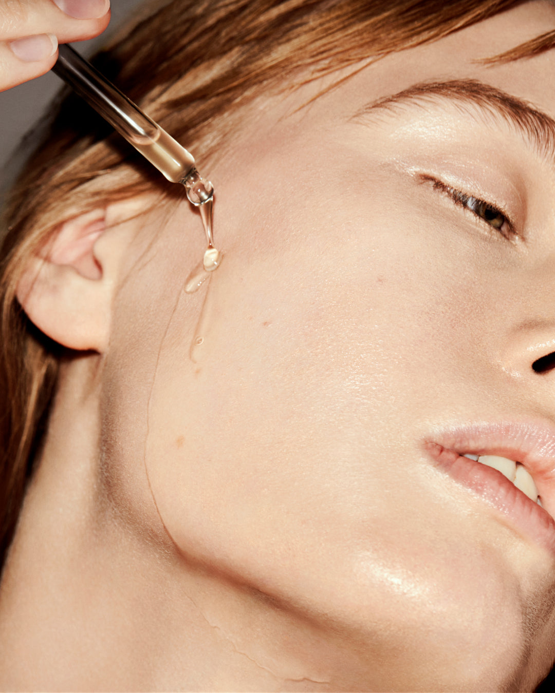 Close-up of a dropper applying liquid to a person's face