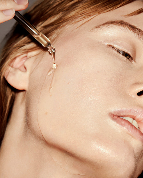 Close-up of a dropper applying liquid to a person's face