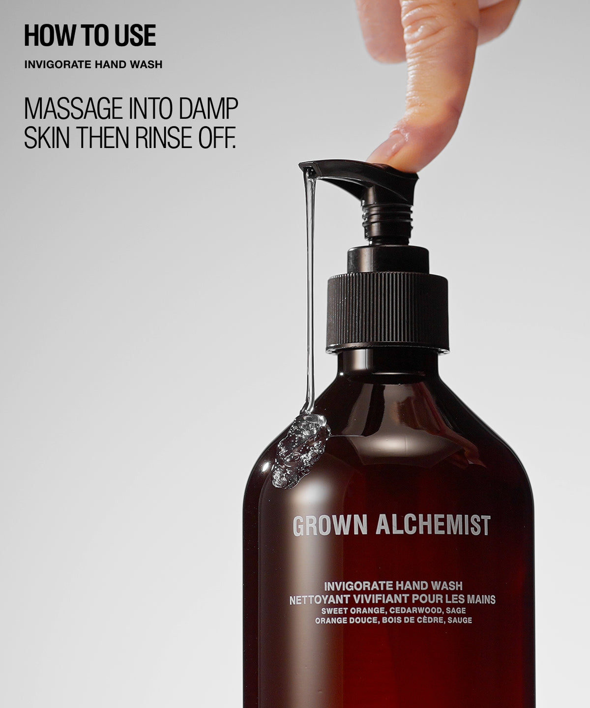 A dark amber pump bottle of Grown Alchemist Invigorate Hand Wash on a light gray background, with a hand pressing the pump and French usage text overlaid on the left.
