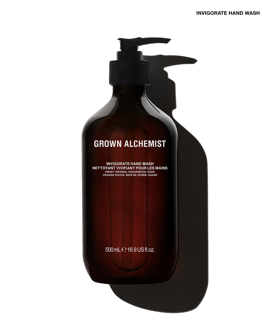 A 500 mL pump bottle of Grown Alchemist Invigorate Hand Wash in a dark amber-brown translucent bottle with a black pump, shown against a white background with a prominent black shadow.